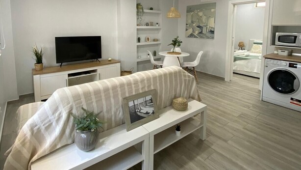 A modern living room with a sofa, TV, and a dining area with chairs and a table. - Apartment "Olhão T1" near the sea with Wi-Fi (Olhão)