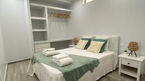 A bedroom with a bed, bedside tables, a built-in wardrobe, and a hanging light fixture. - Apartment "Olhão T1" near the sea with Wi-Fi (Olhão)