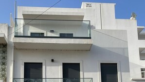 A modern two-story building with a balcony, multiple windows with shutters, and a black door. - Apartment "Olhão T1" near the sea with Wi-Fi (Olhão)