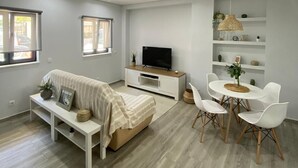 A modern living room with a sofa, TV, dining table, and chairs. - Apartment "Olhão T1" near the sea with Wi-Fi (Olhão)