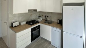 Een moderne keuken met witte kasten, een gasfornuis, een vaatwasser en een koelkast met dubbele deuren.