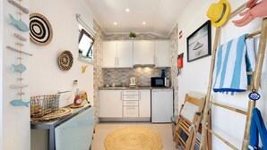 Une cuisine compacte avec des meubles blancs, un four à micro-ondes et un petit évier.