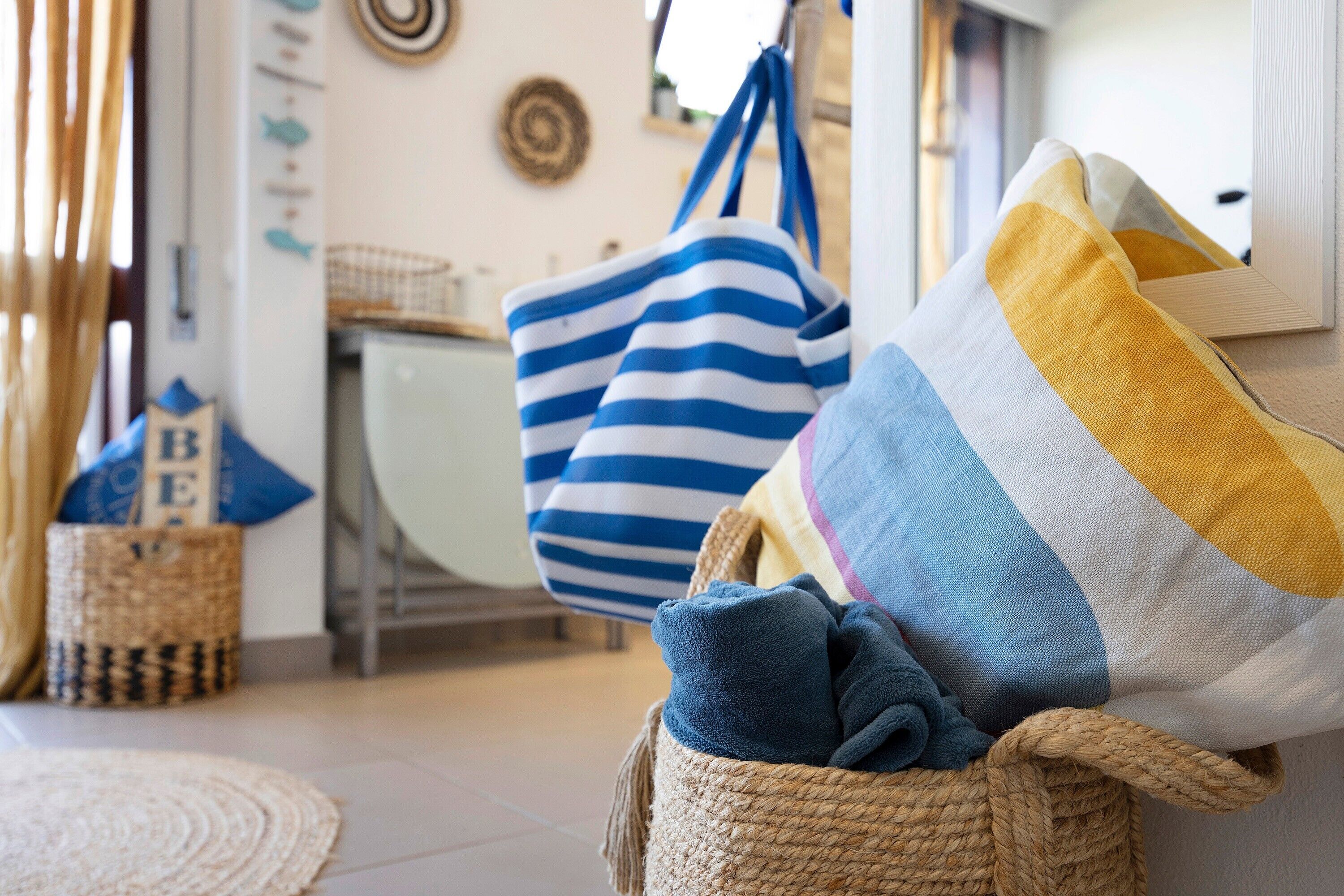 A room with a woven basket, striped bags, and a cushion.
