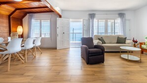 A spacious living area with a wooden ceiling, a sofa, a coffee table, and a dining set. - Holiday Home 'Posidonia' with Sea View, Private Terrace and Wi-Fi (Torrevieja)