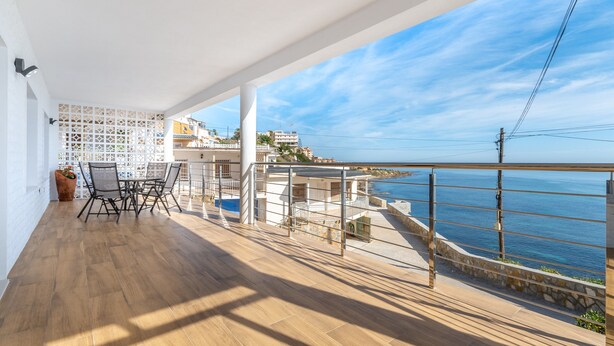 A balcony with a view of the sea, a table with chairs, and a white wall with a lattice design. - Holiday Home 'Posidonia' with Sea View, Private Terrace and Wi-Fi (Torrevieja)