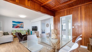 A modern living room with a glass dining table, white chairs, a sofa, and a TV. - Holiday Home 'Posidonia' with Sea View, Private Terrace and Wi-Fi (Torrevieja)