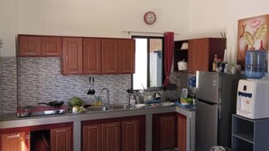 Una cocina con gabinetes de madera, un refrigerador de acero inoxidable, un dispensador de agua y un reloj en la pared.