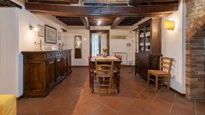 Ein Essbereich mit Holztisch und -stühlen, eine Küche mit Holzausstattung und eine Wand aus Stein.