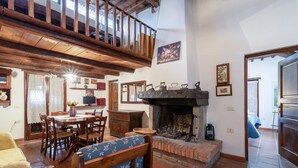 Un interior rústico con comedor, chimenea y escalera de madera.