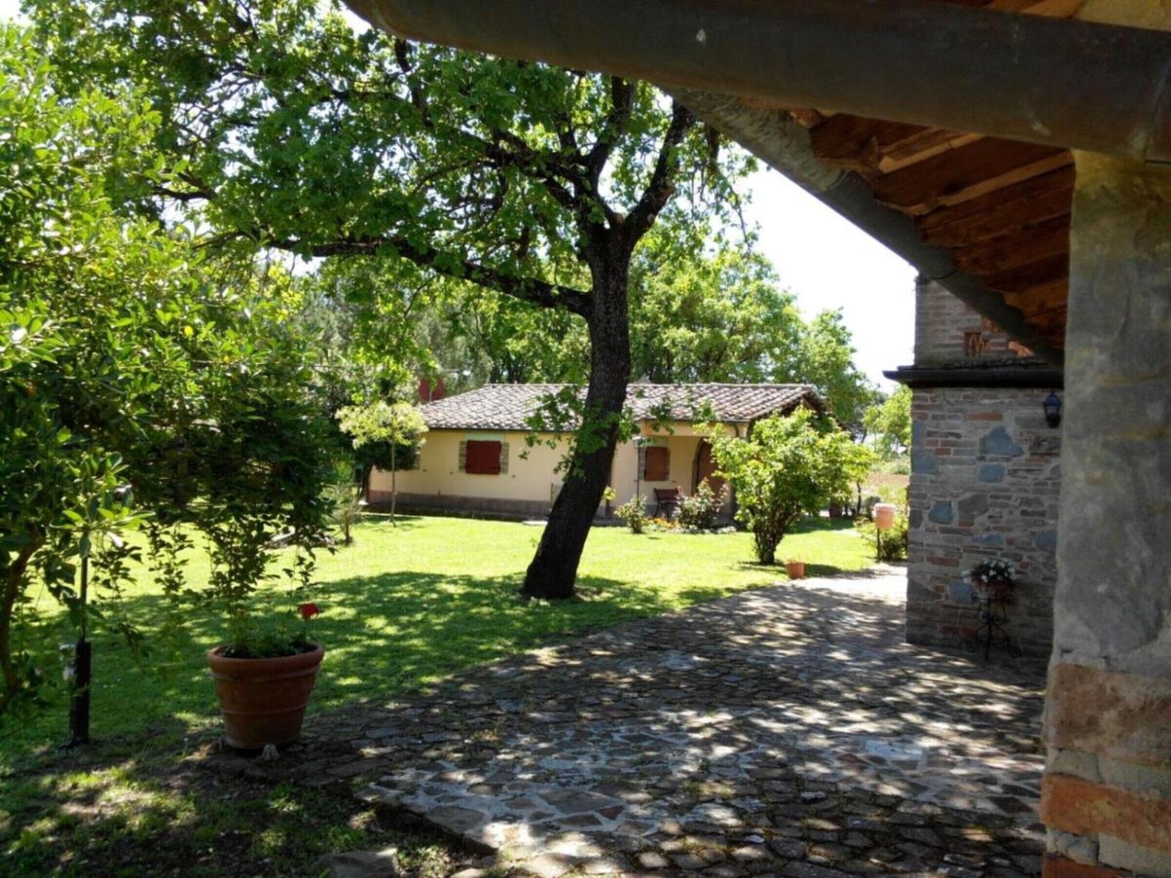 A stone pathway leading to a building with a tiled roof, surrounded by greenery and trees.