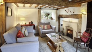 Ein gemütliches Wohnzimmer mit Kamin, einer Couch, einem Sessel und einem Couchtisch.