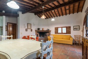 Une pièce avec un lit, un canapé jaune, une cheminée et un plafond en bois.