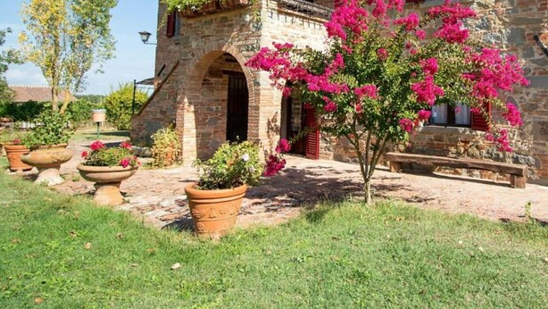 Un bâtiment en pierre doté d’un balcon, d’une arche et de plantes en pot.