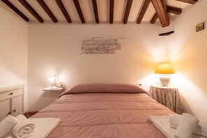 Une chambre à coucher comprenant un lit, des tables de chevet, une lampe et une œuvre d’art accrochée au mur.