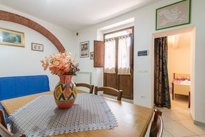 Un comedor con una mesa, sillas, un jarrón con flores y un sofá azul.