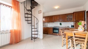 A kitchen with wooden cabinets, a spiral staircase, and a dining area with wooden chairs. - Apartment "Papà Giuseppe Il Fienile" with Shared Pool and Wi-Fi (Cortona)
