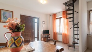 A dining area with a wooden table, a colorful vase, a TV, and a spiral staircase. - Apartment "Papà Giuseppe Il Fienile" with Shared Pool and Wi-Fi (Cortona)