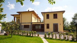 A two-story house with a yellow facade, a stone base, and a small balcony. - Apartment "Papà Giuseppe Il Fienile" with Shared Pool and Wi-Fi (Cortona)