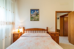 Une chambre à coucher avec un lit, des tables de chevet, une lampe, un tableau et une porte en bois.