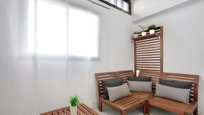 A wooden sofa with patterned cushions, a small wooden table with a plant, and a vertical wooden shelf with potted plants. - Holiday Home 'El Pleito' with Private Pool, Private Terrace and Wi-Fi (Candelaria)