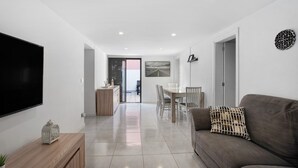 A modern living room with a flat-screen TV, a wooden console, a sofa, and a dining area with chairs and a table. - Holiday Home 'El Pleito' with Private Pool, Private Terrace and Wi-Fi (Candelaria)