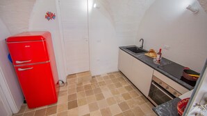 A compact kitchen with a red refrigerator, a sink, and a tiled floor.