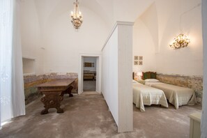A room with a wooden table, two beds, a chandelier, and a view into another room. - Holiday Home "Masseria La Scalella - Fortificato" with Sea View, Terrace & Wi-Fi (manduria)