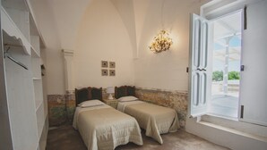 A room with two beds, a chandelier, a window with a view, and a door.
