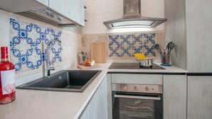 A kitchen with a sink, stove, oven, and decorative blue and white tiles.