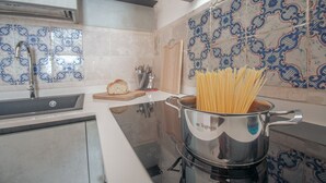 A kitchen with a pot of spaghetti, a sink, and a wooden cutting board.