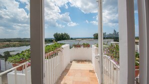 A balcony with potted plants and a view of the landscape.