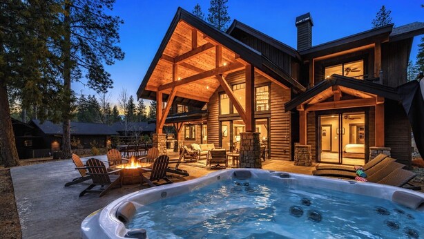 Une cabane en rondins avec un jacuzzi, un espace salon extérieur et une cheminée.