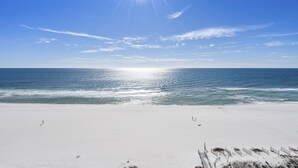 Een strand met wit zand en helderblauw water onder een felle zon.
