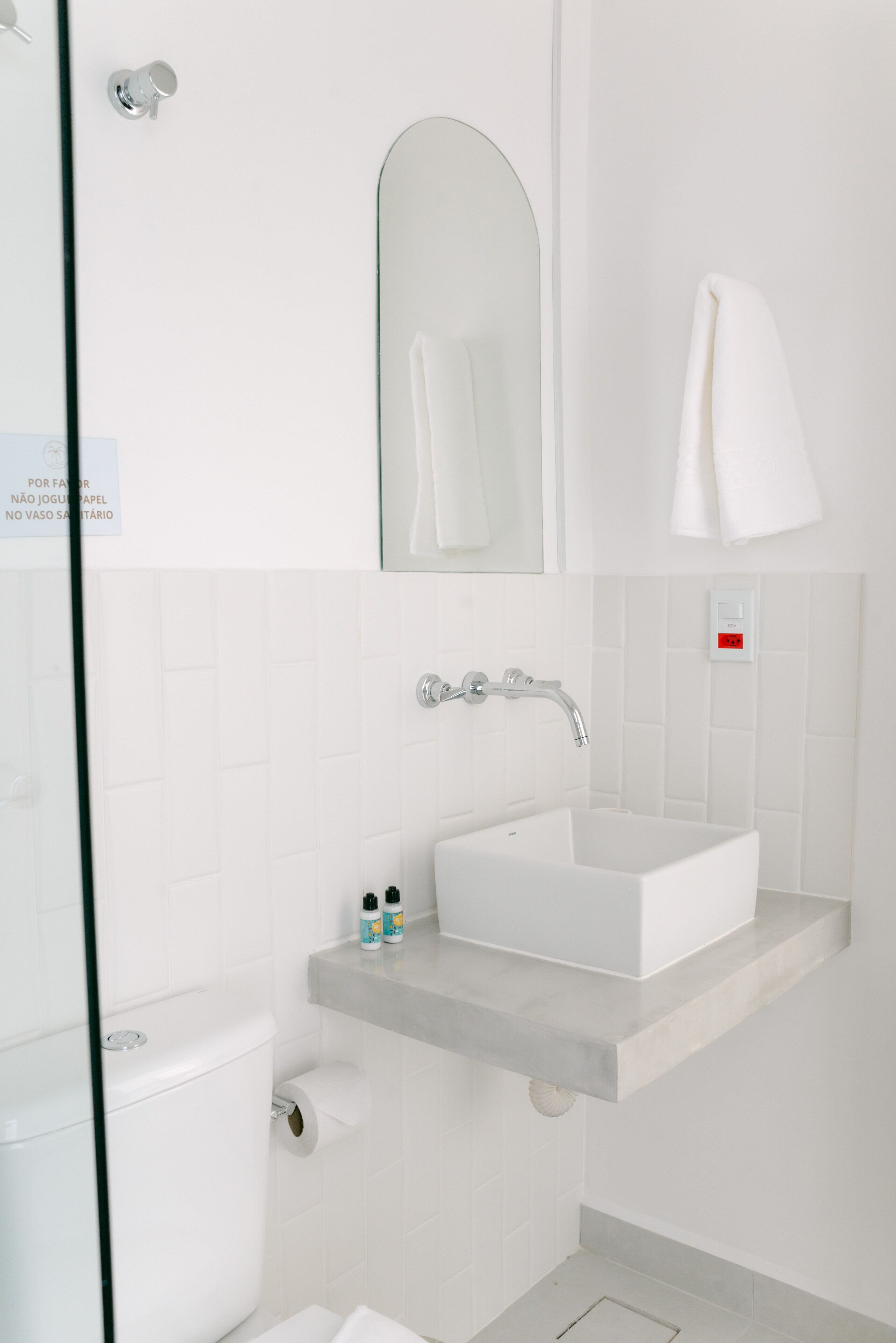 A bathroom with a white sink, a mirror, a towel rack, and a toilet.