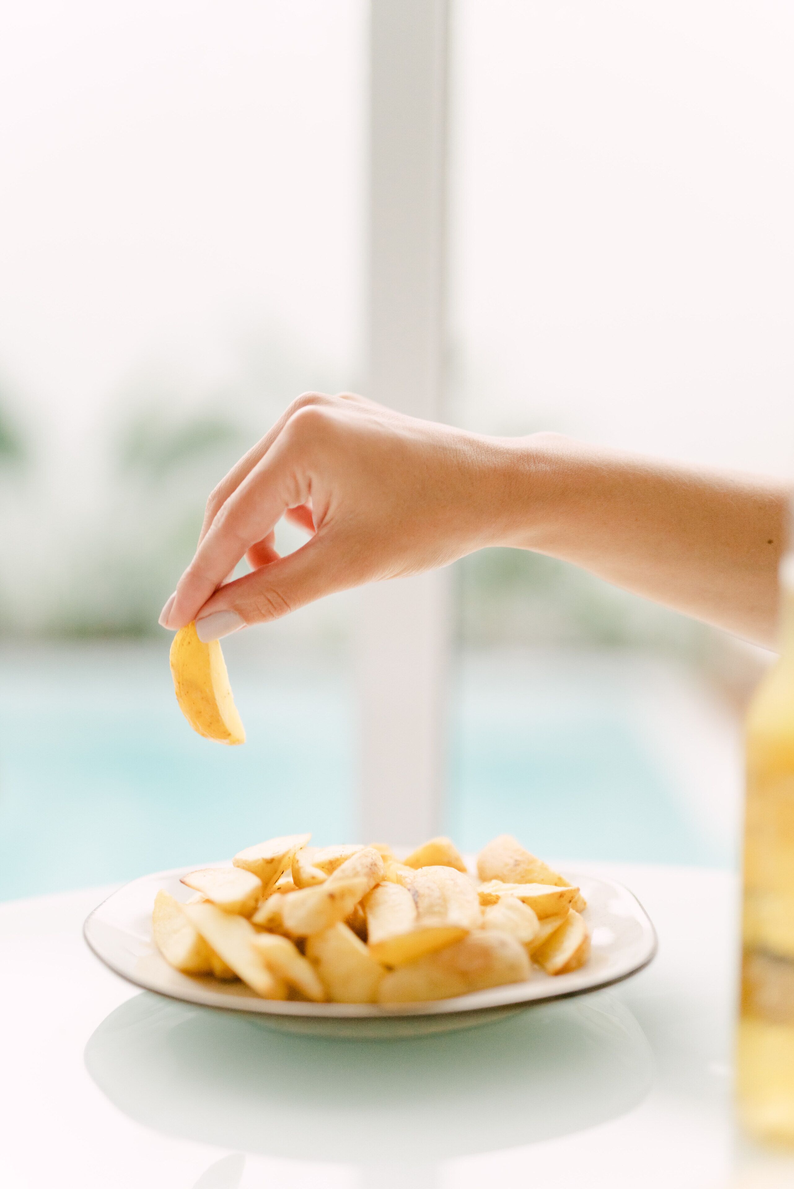 Une main qui prend une banane dans une assiette remplie de tranches de bananes.