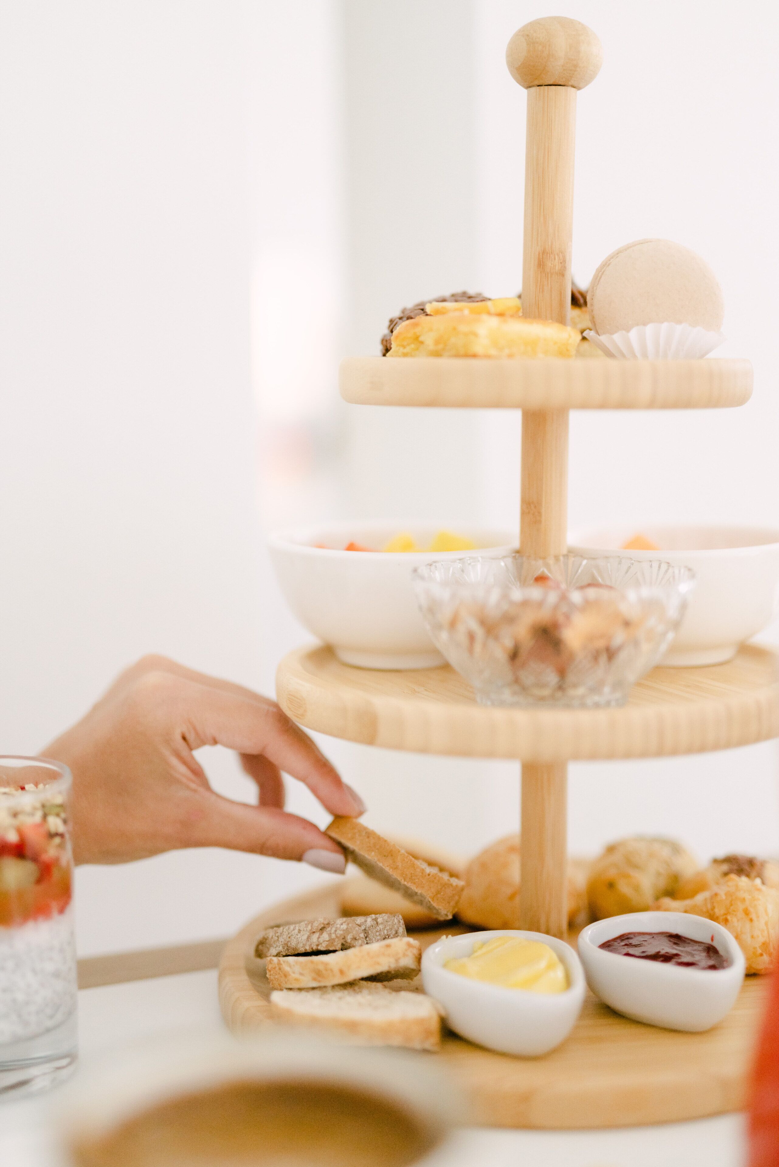 A multi-tiered wooden serving tray with various food items and condiments.