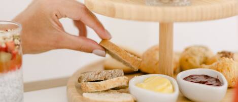 A multi-tiered wooden serving tray with various food items and condiments.