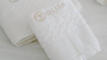 Toalhas brancas dobradas com a marca 'OLISA' em relevo.