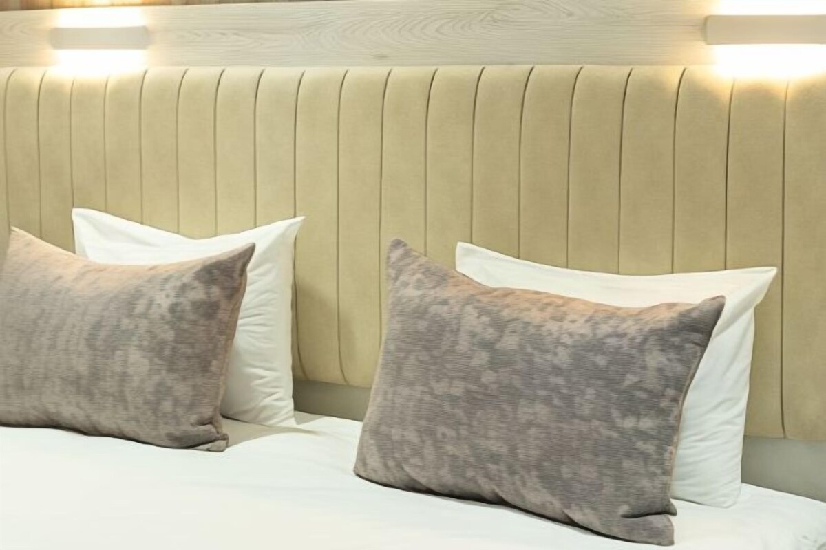 Una cama con dos almohadas y un panel de cabecera de madera.
