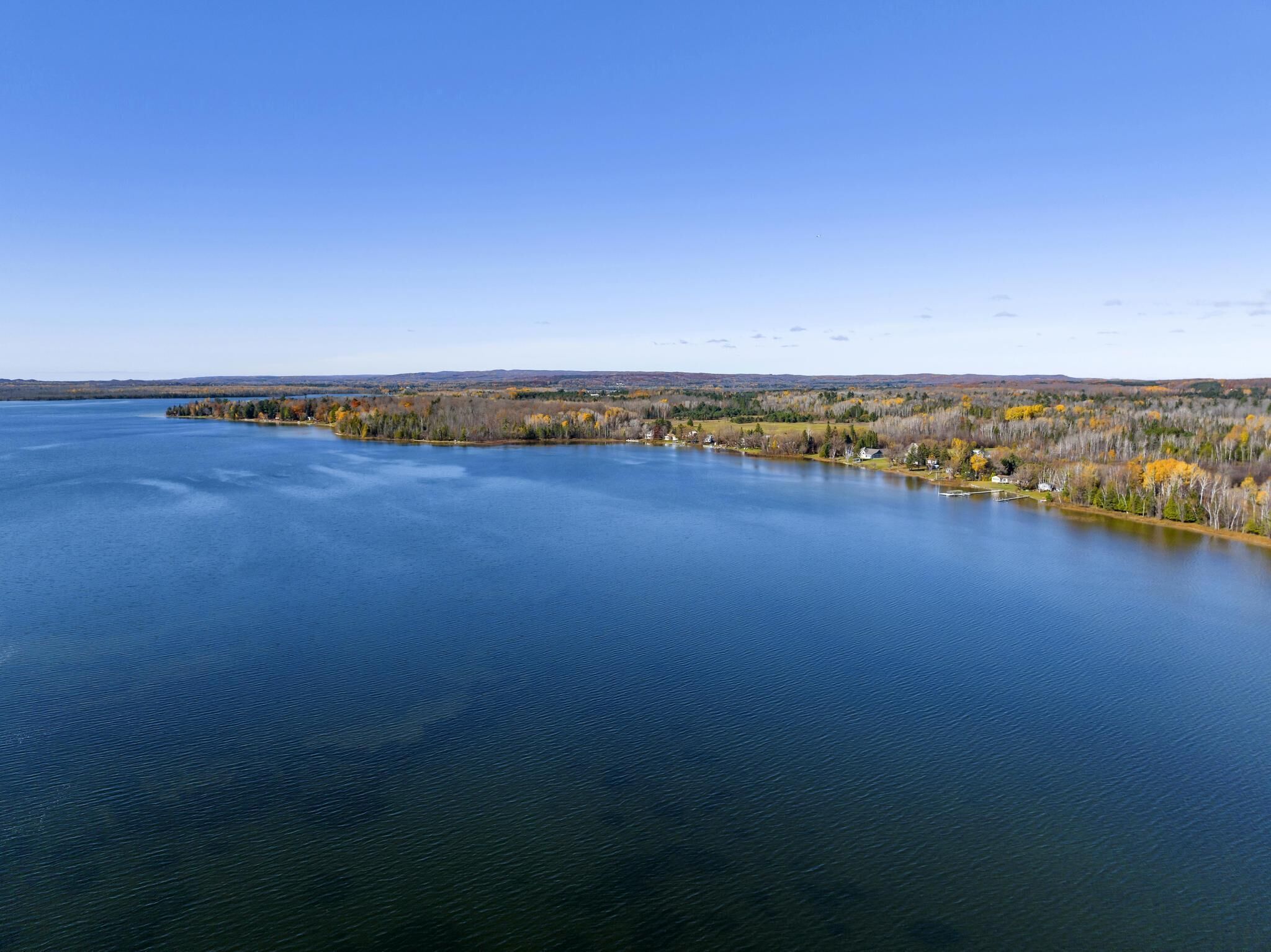 A large body of water with a forested shoreline and distant hills.