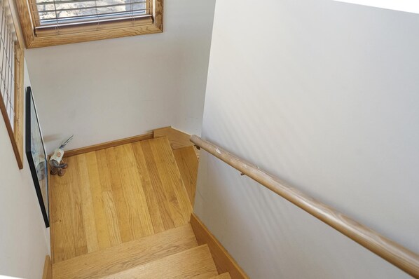 A wooden staircase with a handrail, a small window with a wooden frame, and a wall-mounted radiator. - The Sweet Seclusion Cottage with 100 feet of Private frontage Pickerel Lake! (Alanson)