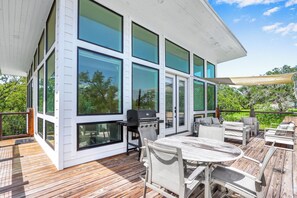 Une maison moderne dotée d’une terrasse, de grandes fenêtres et de mobilier d’extérieur.