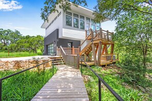 Un bâtiment moderne à deux étages, doté d’une terrasse en bois et d’un escalier menant à un balcon.