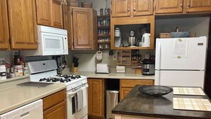 Una cocina con armarios de madera, una estufa blanca, un lavavajillas y un refrigerador.