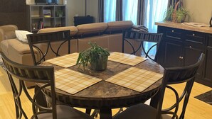 A dining area with a round table, four chairs, and a potted plant.