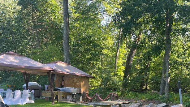 A rustic outdoor setting with a stone wall, picnic table, and covered seating area.