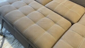 A sectional sofa with a tufted design and metal legs.