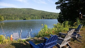 Une vue sur le lac, avec des fauteuils Adirondack et une jetée qui s’avance dans l’eau.