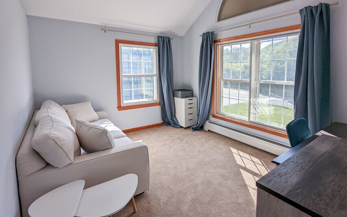Une chambre moderne avec un canapé, un bureau et de grandes fenêtres.