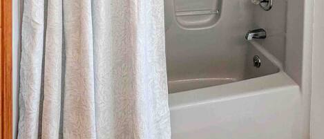 Un baño moderno con bañera, ducha y cortina.